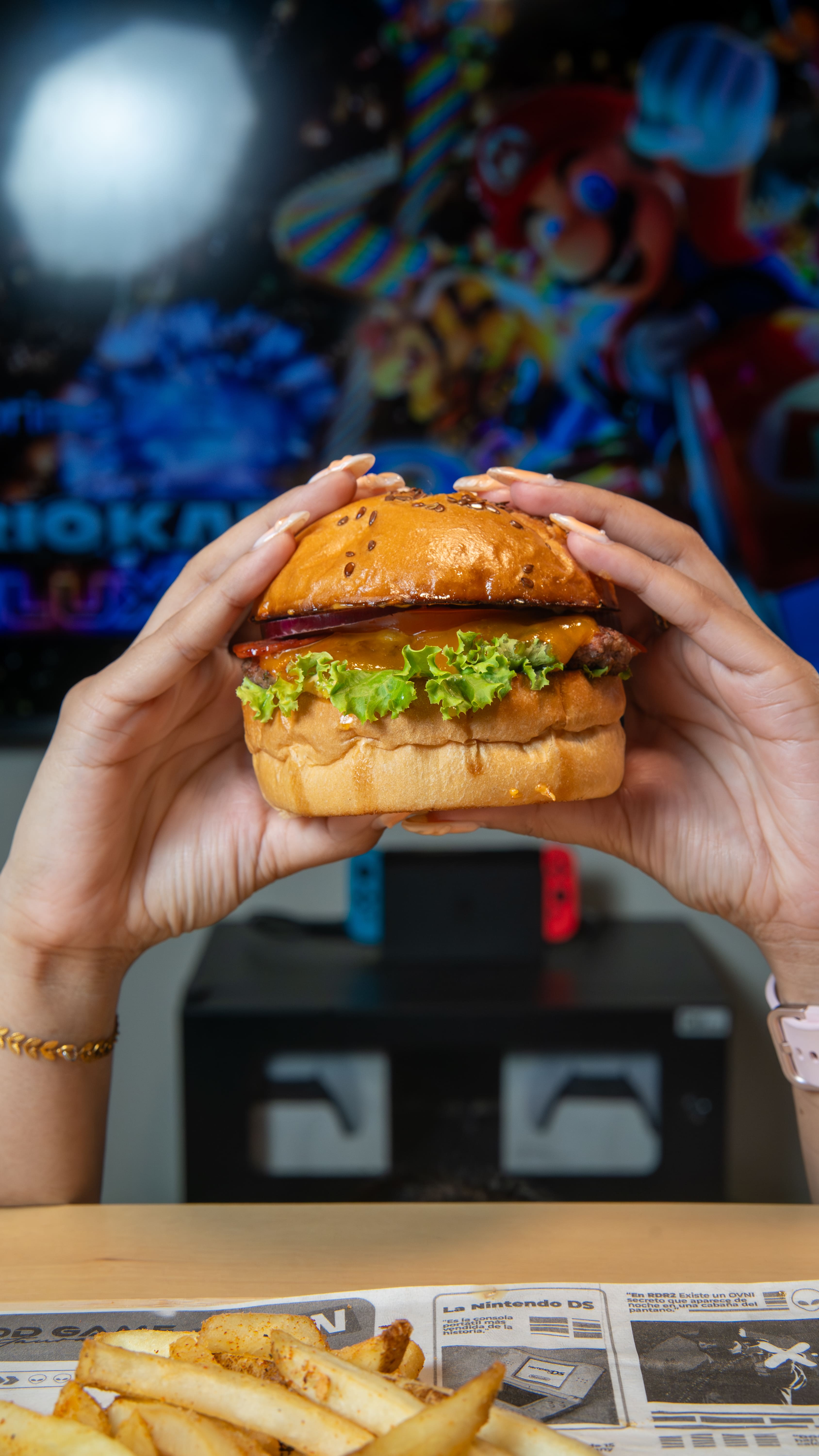 Plano detalle vertical que muestra unas manos sosteniendo una hamburguesa